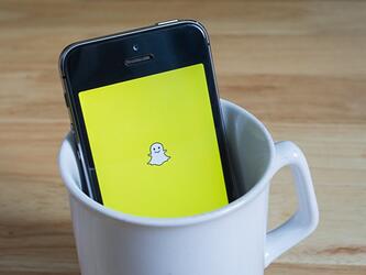 snapchat logo on phone in mug